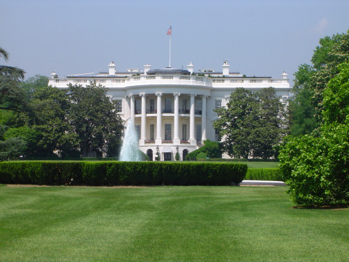 Scenic view of the exterior of the White House, Washington DC viewed across manicured green lawns on a sunny summer day